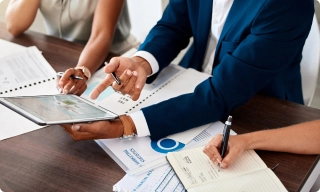 Réunion de travail autour d’un expert-comptable analysant des données financières avec des entrepreneurs.