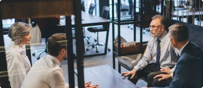 Discussion entre un expert-comptable et des clients dans un espace confidentiel, illustrant l’écoute et l’accompagnement personnalisé pour des demandes spécifiques.