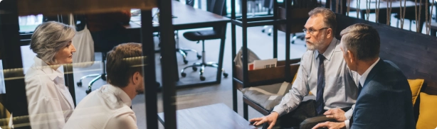 Discussion entre un expert-comptable et des clients dans un espace confidentiel, illustrant l’écoute et l’accompagnement personnalisé pour des demandes spécifiques.